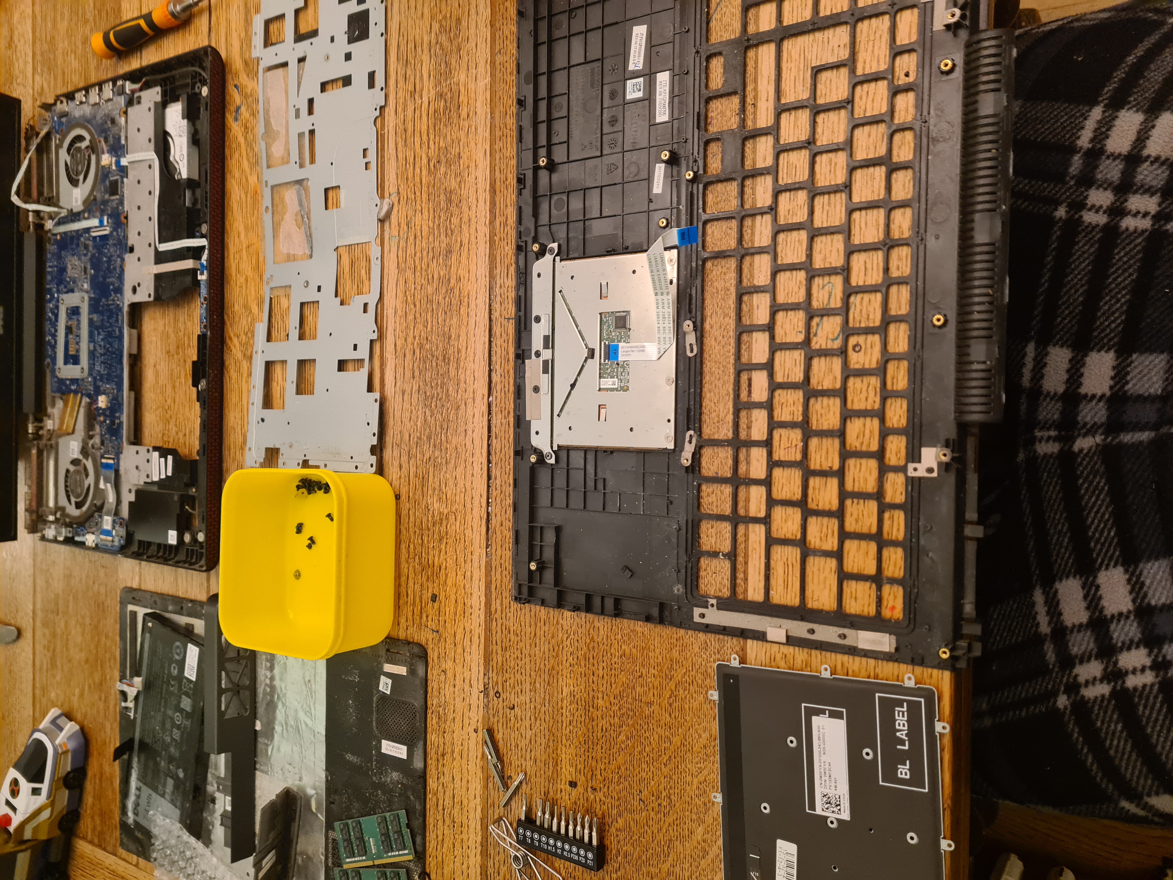 The Inspiron stripped down — motherboard, chassis and keyboard frame all separated out on the workbench