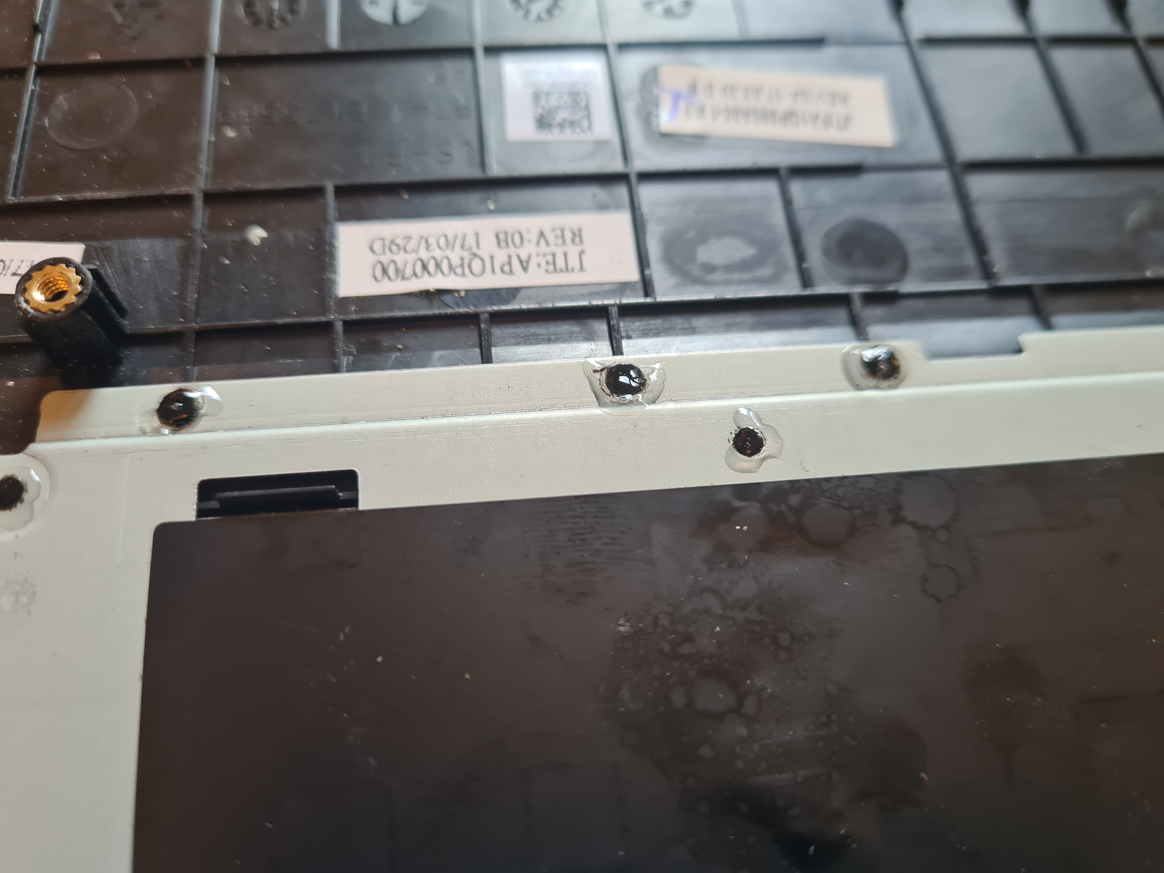 Close-up of the superglued plastic pegs holding the keyboard bracket in place